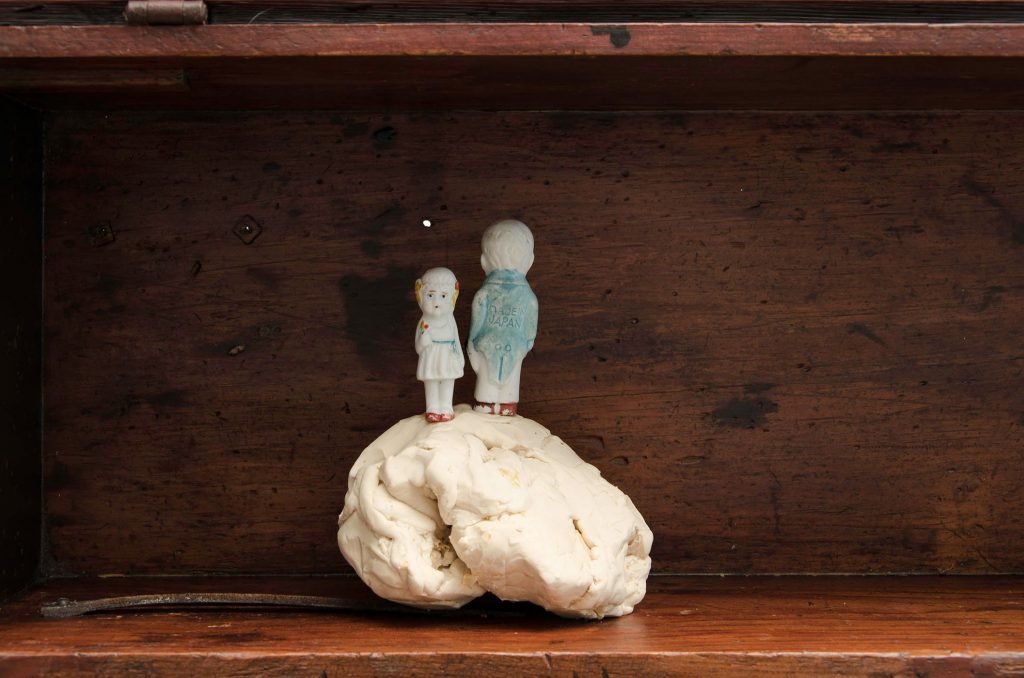 Two tiny toy figures standing on a white clay ball